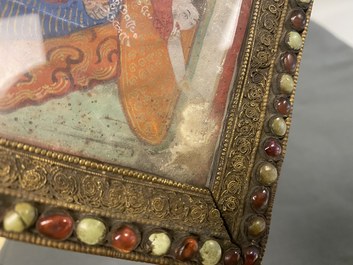 A Tibetan thangka in inlaid gilt brass frame, 19th C.